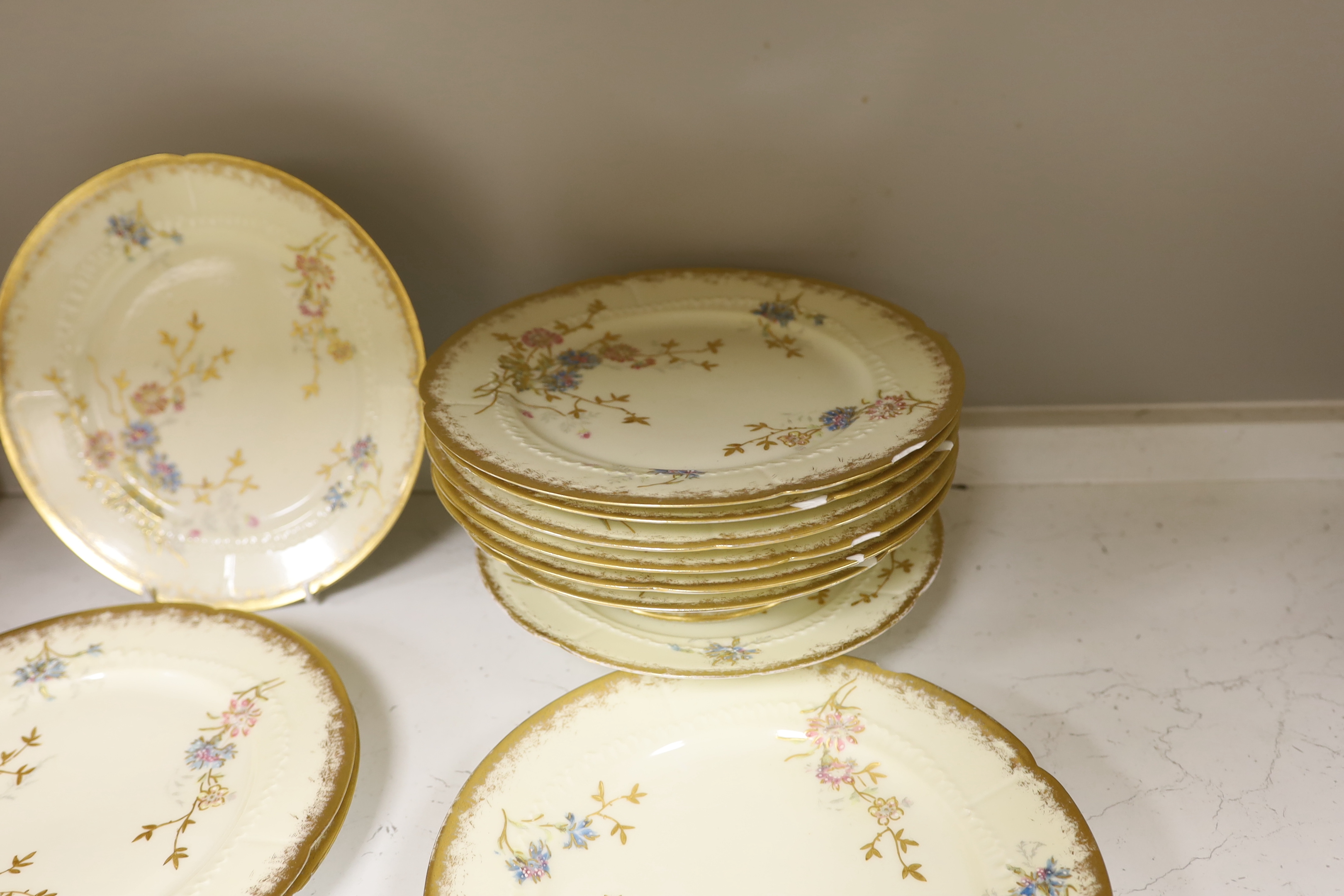 Thirteen Limoges style porcelain dessert plates, two on pedestal bases, gilt decorated with cornflowers etc., 24.5cm diameter